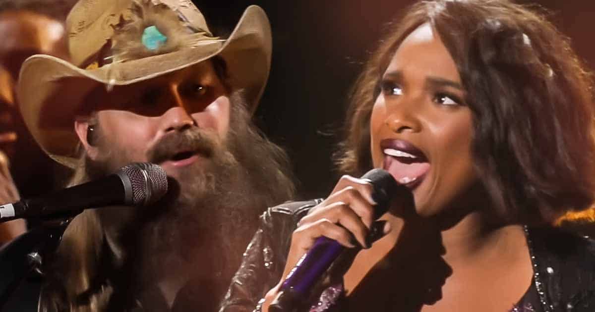 Jennifer Hudson and Chris Stapleton performing together on stage at the CMA Awards, delivering a powerful and unforgettable duet under dramatic stage lighting.